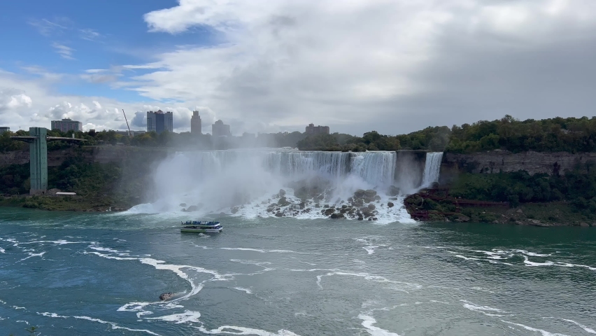 panoramic view of Niagara Falls from the Canadian side of the river with two of three individual falls, the American Falls and the Bridal Veil Falls located on United States side - with tourist boat 