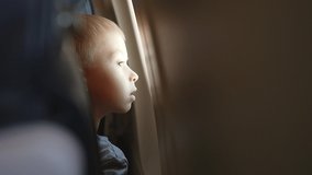 Side view from back seat, child looks out window of an airplane in flight. Tourist travel lifestyle. Looking aerial view of sky and cloud. Look around indoors. Sleepy tired baby boy in transport. - Powered by Shutterstock - Get 15% off with code: PIKWIZARD15