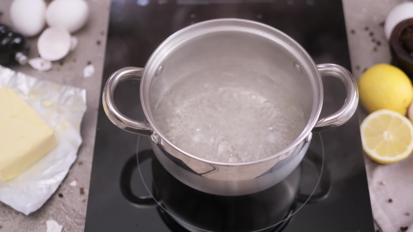 Setting up bain-marie Pot of boiling water on a induction hob Royalty-Free Stock Footage #1094766697