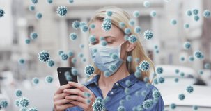 Animation of virus cells over caucasian woman wearing face mask and using smartphone. global covid 19 pandemic and health concept digitally generated video.