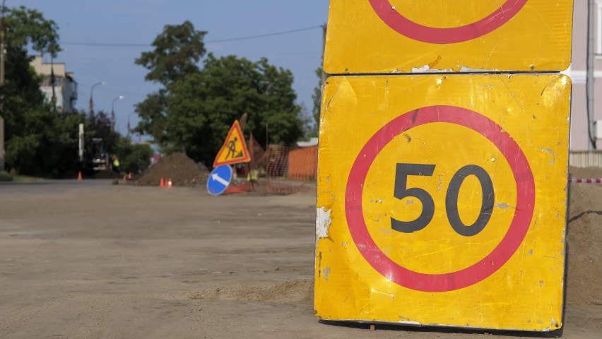 Road sign speed limit 50 km h in combination with road work ahead. Warning signs for work in progress on closed road under construction with arrow sign and traffic cone, hinders traffic in the city.