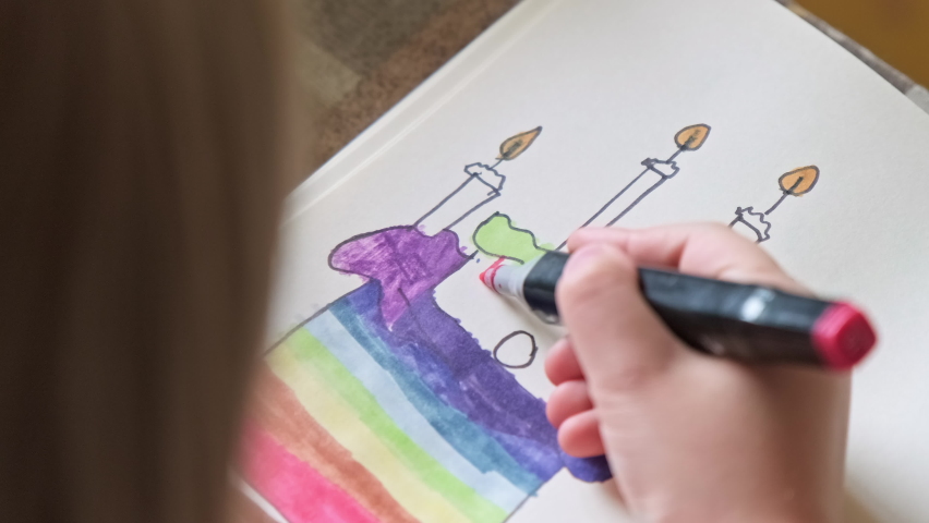 Child draws cake with candles with felt pen on paper. Girl enjoys painting process. Little girl painting. Close-up in 4K, UHD | Shutterstock HD Video #1094778353