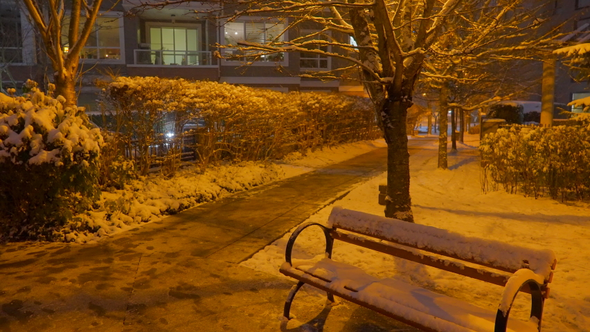Establishing shot of modern apartment building with beautiful winter snowfall landscape at night in Vancouver, Canada, North America. Night time on December 2021. ProRes 422 HQ.