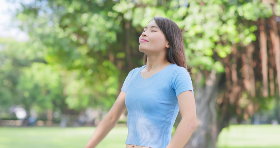 asian carefree woman take deep breath and stretching her arms in the park Royalty-Free Stock Footage #1094782463