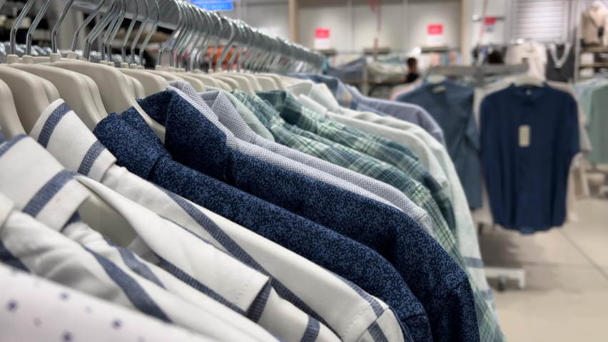 Men's shirts hang in rows on hangers in a clothing store. Close-up | Shutterstock HD Video #1094782549