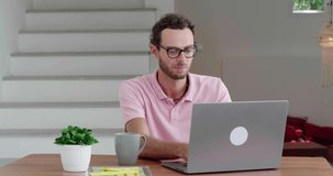 Concentrated handsome Caucasian businessman, freelance worker, experienced programmer typing text on keyboard while writing computer programs when working remotely on laptop in comfy home office.