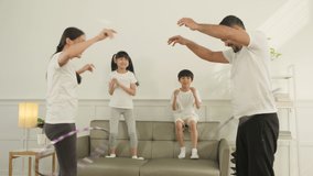 Happy wellness Asian Thai family, parents, and children are fun playing hula hoops together, fitness training and healthy exercise in white living room, domestic home lifestyle, and weekend activity. - Powered by Shutterstock - Get 15% off with code: PIKWIZARD15