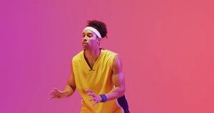 Video of biracial male basketball player catching ball on orange to pink background. Sports and competition concept.