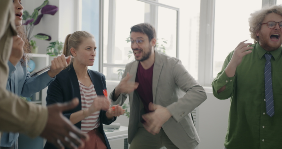 Cheerful businesspeople are playing darts laughing doing high-five in modern office. Workplace fun and Royalty-Free Stock Footage #1094787071
