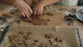 Unrecognizable woman with daughter making gingerbread cookies with dough and putting them on baking tray. Shot with RED helium camera in 8K.   