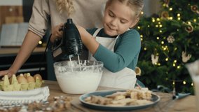 Caucasian mother and daughter preparing baking using electric mixer in the kitchen before Christmas. Shot with RED helium camera in 8K.  