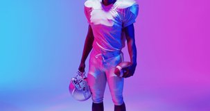 Video of portrait of african american american football player over blue to pink neon background. American football, sports and competition concept.