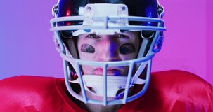 Video of portrait of caucasian american football player in helmet over neon purple background. American football, sports and competition concept.