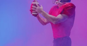 Video of caucasian american football player in helmet with ball over neon purple background. American football, sports and competition concept.