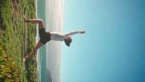 Yoga exercises with ocean view on background. Caucasian woman doing yoga training on seashore. Healthy lifestyle concept. Mid adult female practicing yoga and flexibility. Vertical video Warrior pose