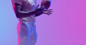 Video of african american american football player with copy space over blue to pink neon background. American football, sports and competition concept.