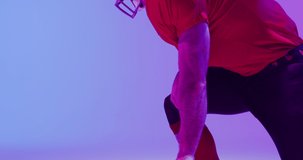 Video of caucasian american football player in helmet over neon purple background. American football, sports and competition concept.