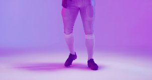 Video of african american american football player with ball over purple background. American football, sports and competition concept.