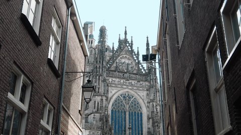 dolly through alleyway towards facade of gothic cathedral in center den Bosch Adlı Stok Video