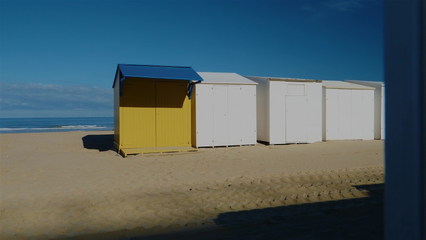 Desolate beach cabins standing next to each other on beach with ocean in the background
