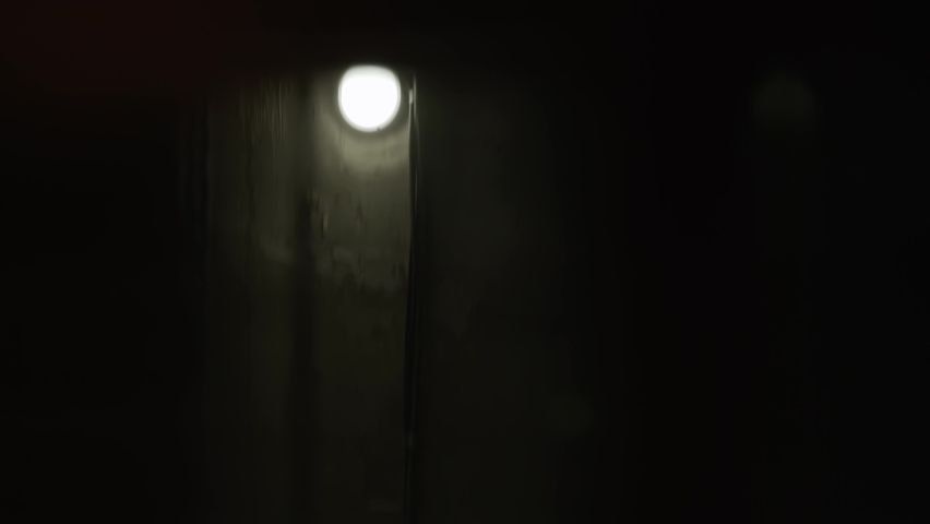 Climbing technical hoist through elevator shaft, close-up. Turned on incandescent lamps with cold light on concrete wall of the technical pit move down. Royalty-Free Stock Footage #1094802605