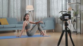 Full View Of Young Asian Trainer Female In Sports Clothes Speaking To Camera And Doing Crisscross Crunch Workout While Recording Teaching Exercise At Home
