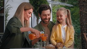 Caucasian family on camping vacation outdoors sitting near van have lunch picnic eat good with croissants mother pouring fresh orange juice into glasses for father husband and child little daughter - Powered by Shutterstock - Get 15% off with code: PIKWIZARD15