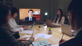 Business people group remote meeting with manager leader via video call conference virtual meeting on tv screen in office at night
