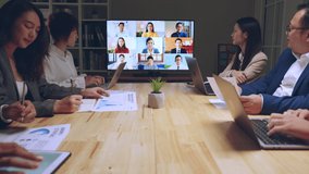 Business people group remote meeting with colleagues via video call conference virtual meeting on tv screen in office at night - Powered by Shutterstock - Get 15% off with code: PIKWIZARD15
