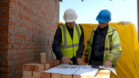 Two construction workers Looking on Blueprint Project Plans on construction site. Builder On Building Site Looking At Plans  - Powered by Shutterstock - Get 15% off with code: PIKWIZARD15