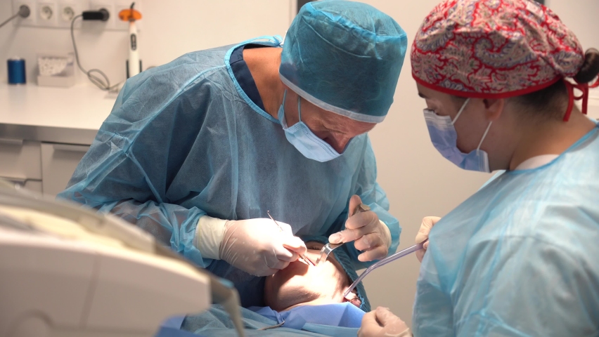 Dental clinic, dentist doctor and the assistant with blue suits performing an operation of an implant Royalty-Free Stock Footage #1094818511