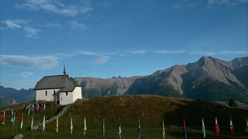 Landscape of church and mountains. Real time of church with Swiss canton flags. Bettmeralp, Switzerland.
