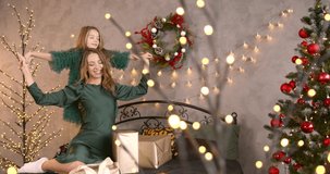 Mother and daughter hugging and posing near xmas tree