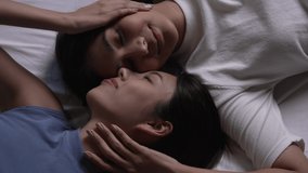 High angle view of smiling Asian lesbian couple relaxing and lying down in bed. LGBT couple lifestyle concept. - Powered by Shutterstock - Get 15% off with code: PIKWIZARD15