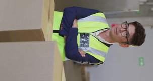 Vertical video of portrait of asian male worker with boxes in warehouse. global shipping and delivery business.