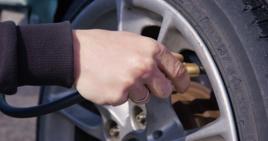 Person hand takes out car pump hose nozzle after pumping wheel tire for driving. Driver makes sure about quality of inflated tires for drifting Royalty-Free Stock Footage #1094823989