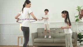 Happy wellness Asian Thai family, parents, and children are fun playing hula hoops together, fitness training and healthy exercise in white living room, domestic home lifestyle, and weekend activity. - Powered by Shutterstock - Get 15% off with code: PIKWIZARD15