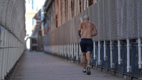 4K video with a bare-chested man running and jogging on the pedestrian path from Manhattan Bridge. Sport is good at any age.