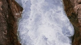 Mountain river. A rapid flow of clean water trapped between rocks. Bubbling water, foam and splashes. Water flow in a mountain gorge, view of the water. natural background. Slow motion video 120 fps.