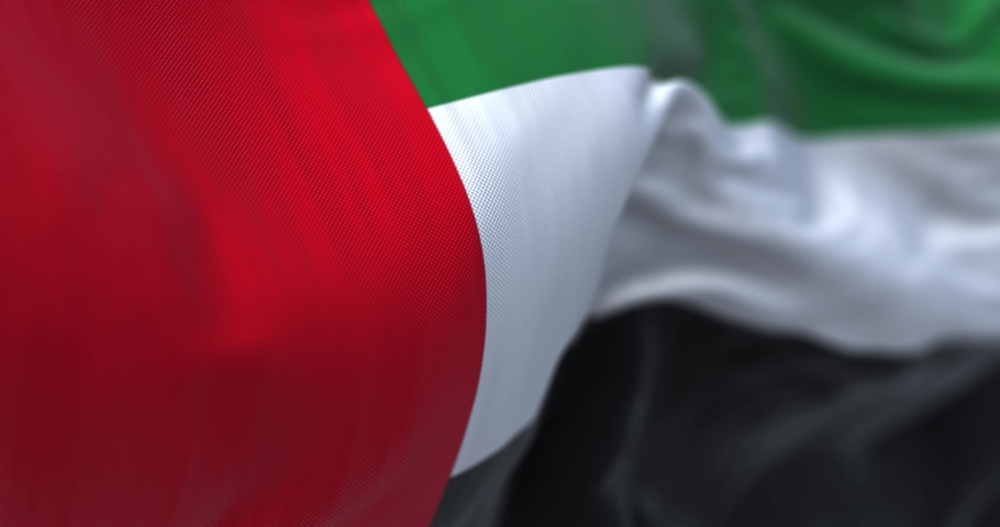 Close-up view of the United Arab Emirates national flag waving in the wind. The Emirates is a country in Western Asia. Fabric textured background. Selective focus. Seamless loop in slow motion Royalty-Free Stock Footage #1094837637