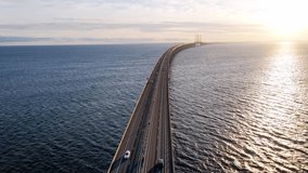Drone flying over an Oresund bridge at the sunset in summer. Cinematic shot of long tunnel bridge between Sweden and Denmark. Oresund bridge from the top. High quality 4k footage