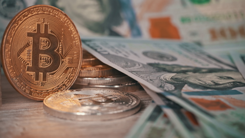 Gold coin of bitcoin on the background of one hundred dollar bills. Cryptocurrency is measured in dollars. Bitcoin BTC coin on 100 dollar bill. Cyberspace of digital coins and cryptocurrencies.