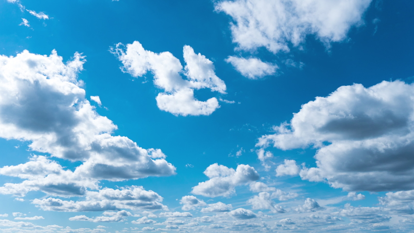 White fluffy clouds slowly float through the blue daytime sky timelapse. Beautiful skies are moving. Airy snow-white clouds move to the side. Royalty-Free Stock Footage #1094843575