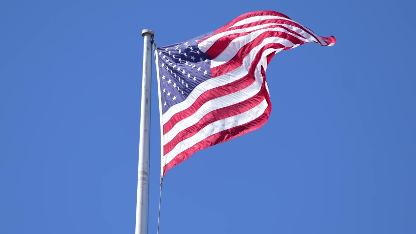National flag of America winding in sunlight against perfect blue sky, 4K concept video for United States of America | Shutterstock HD Video #1094844023