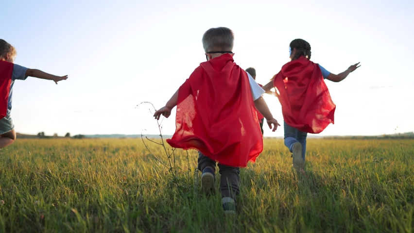 Happy family. Children dressed as superheroes play in the park. Superhero teamwork. Strong children dream of victory. Children are superheroes winners. Family game in nature. Superheroes in red capes Royalty-Free Stock Footage #1094845399