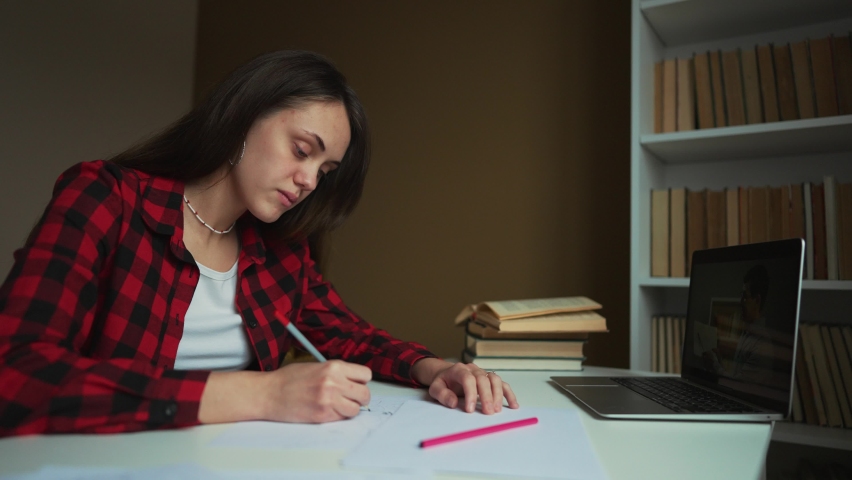 Girl of the student studies at home remotely. The student is engaged with the help of a service on a computer. The girl uses a computer and its services to study at home. Online school new normal | Shutterstock HD Video #1094845457