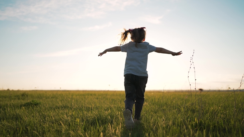 Happy girl in field on the grass. A small child runs in park in summer. Freedom and joy of child in nature. Family rest and game on a green meadow. The winner girl runs towards her dream. baby winner Royalty-Free Stock Footage #1094845461