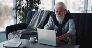 Elderly pensioner caucasian male businessman talking on laptop webcam videochat blogging job interview at home interior. Modern lifestyle.