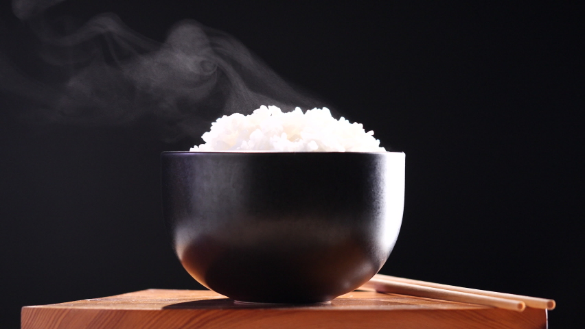 Japanese rice, Cooked rice. Close up natural steaming cooked Japanese white rice in black bowl with chopstick on black background, soft focus. Healthy Food Concept. Royalty-Free Stock Footage #1094846437
