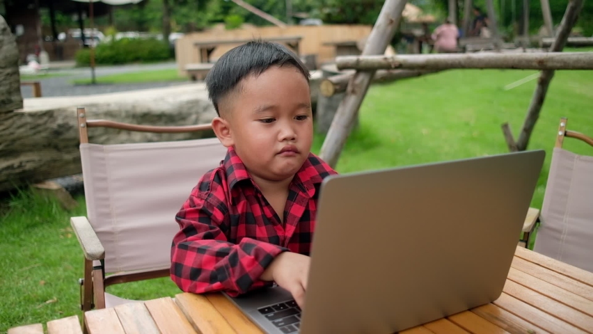 Boy using laptop while attending the online classes in garden. internet learning. new normal. | Shutterstock HD Video #1094849985